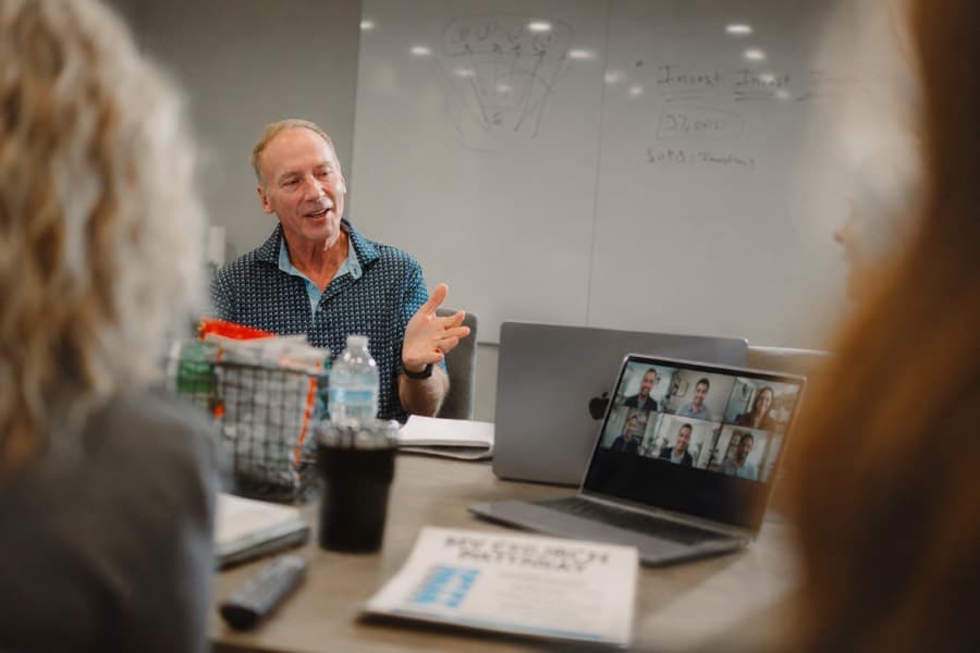 Mike Bodine speaking with his team, with an Executive Network video call visible on a laptop